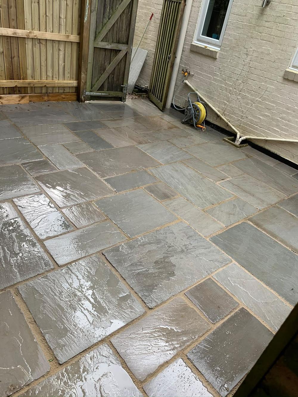 Grey sandstone patio finished against a house