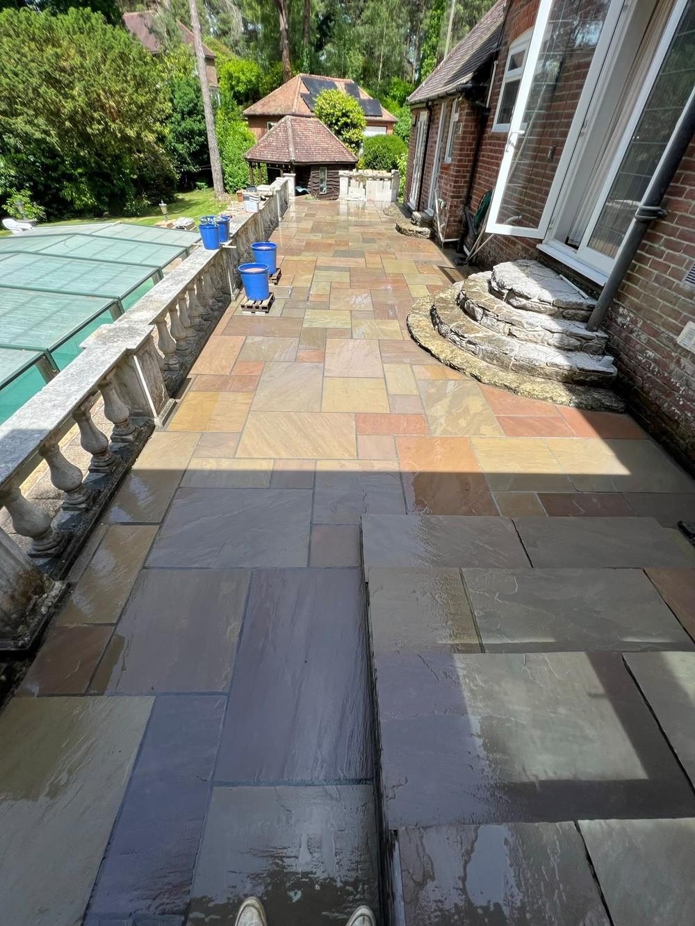Sandstone patio beside a pool with stone balustrade